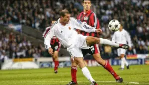 Zidane-ähnlicher Moment: Fußballspieler in weißem Trikot setzt zum Kick gegen Gegenspieler in roter Uniform an, grün-blauer Stadionhintergrund, dynamische Bewegung