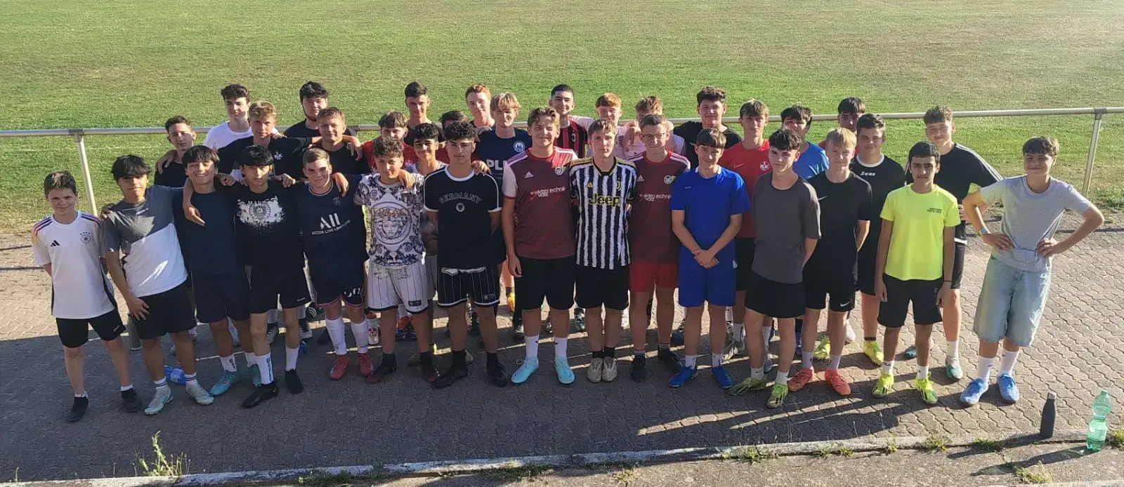Eine Gruppe von Jugendlichen in Sportkleidung steht auf einem Fußballplatz und posiert für ein Foto.