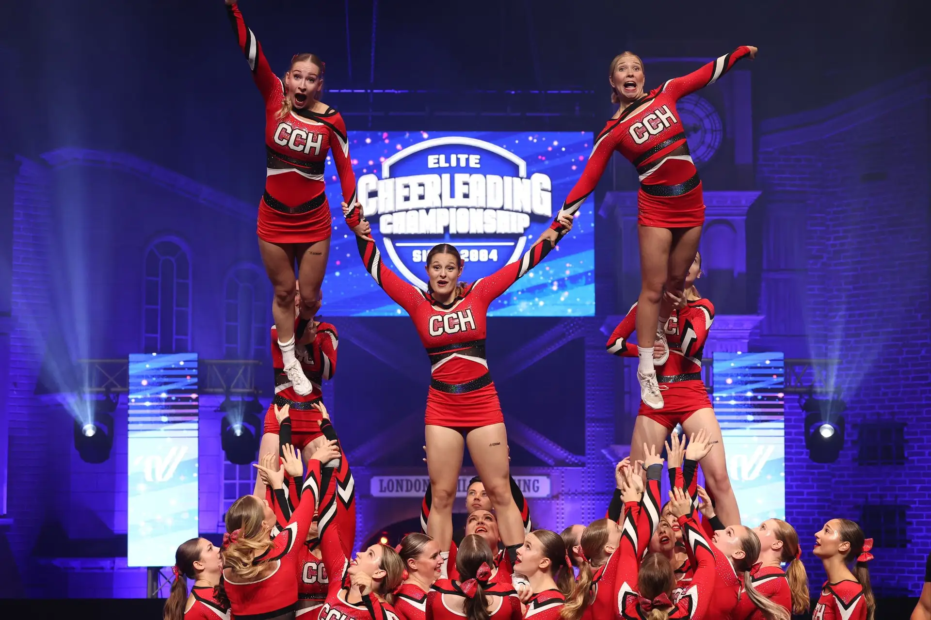 Cheerleading-Team führt eine Gruppenstunt-Performance auf einer Bühne während einer Meisterschaft durch.